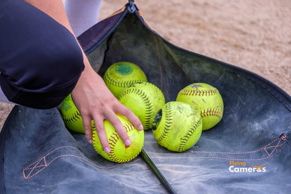 Hand selects a yellow baseball from bag of baseballs