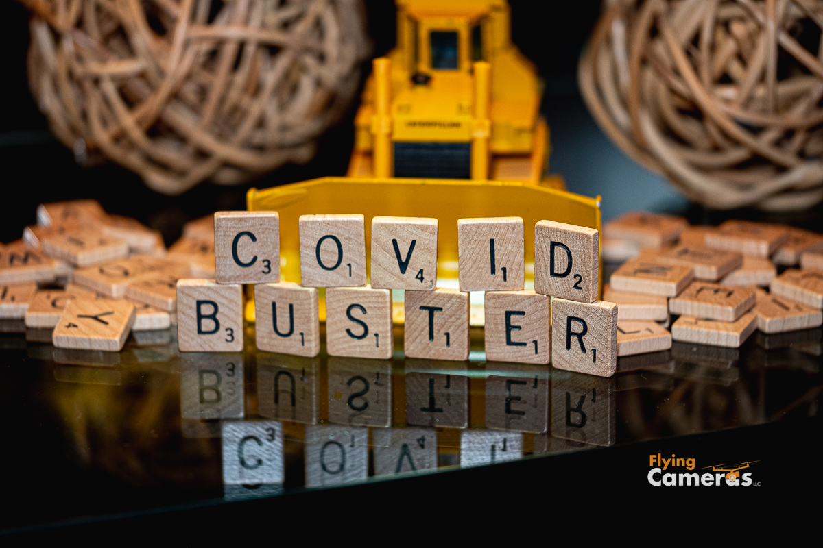 Toy bulldozer breaking scrabble tiles (totaling 19) spelling covid buster 