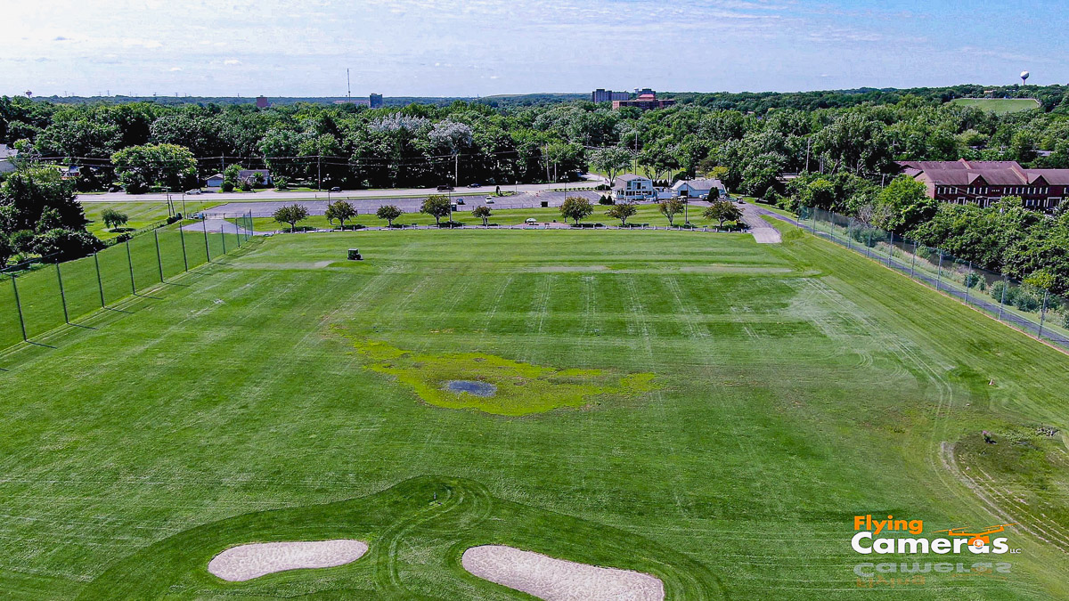 Image of a golf driving range with lush green grass taken at 225 ft from a drone